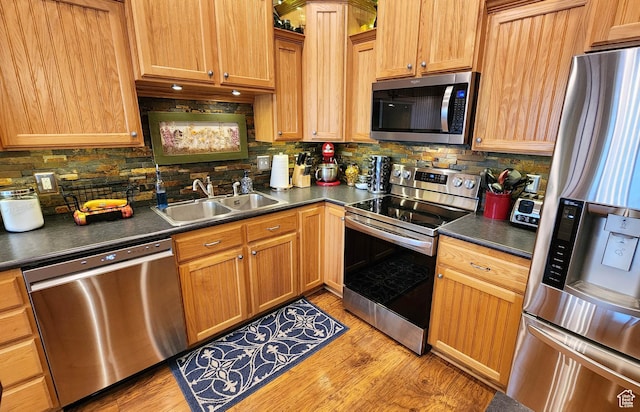 6723 W Hunter Farm Cir S, West Valley City, UT 84128 - kitchen featuring appliances with stainless steel finishes, a sink, dark countertops, light wood-type flooring, and backsplash