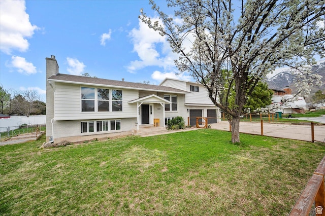 1308 Gilman Dr, Layton, UT 84040 - raised ranch featuring fence, a front lawn, a chimney, a garage, and concrete driveway
