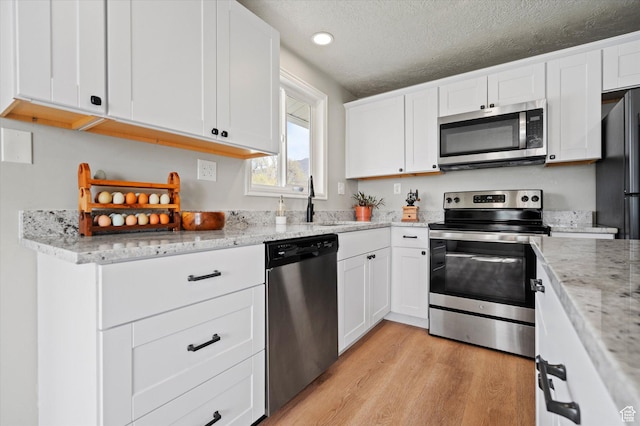 1308 Gilman Dr, Layton, UT 84040 - kitchen with light stone counters, stainless steel appliances, a sink, light wood-style floors, and white cabinetry