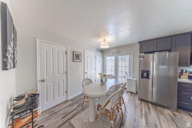 dining room with a textured ceiling and light wood finished floors