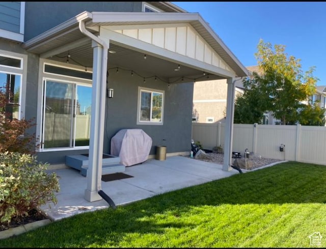 back of property featuring fence, a patio area, a yard, stucco siding, and board and batten siding