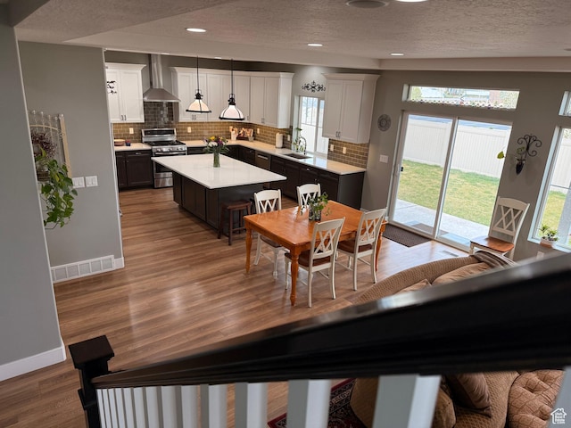 interior space with recessed lighting, a textured ceiling, baseboards, visible vents, and wood finished floors