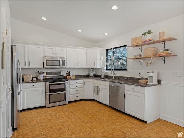 kitchen featuring white cabinets, appliances with stainless steel finishes, dark stone counters, and a sink