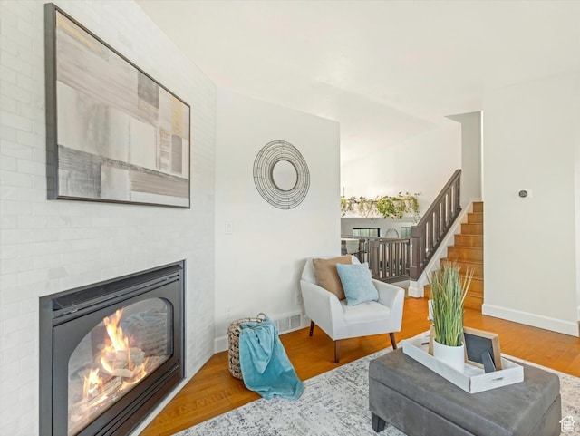 sitting room with stairway, baseboards, wood finished floors, and a fireplace