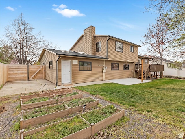 back of property featuring a gate, a patio area, a chimney, fence, and a garden