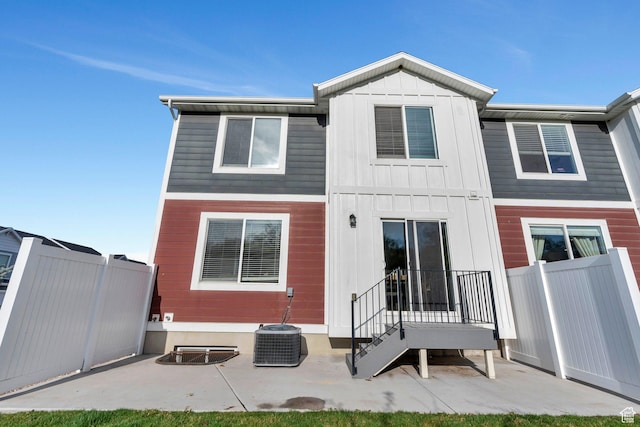 rear view of property with fence, a patio, and board and batten siding