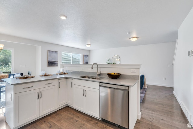 kitchen featuring dark wood-type flooring, a peninsula, stainless steel dishwasher, and a sink