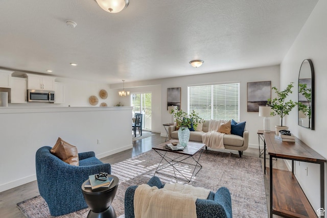 living room featuring baseboards, a chandelier, and wood finished floors