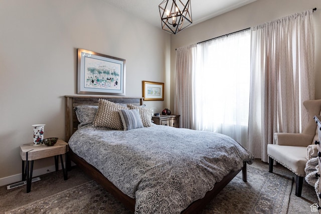 carpeted bedroom featuring visible vents, baseboards, and a notable chandelier