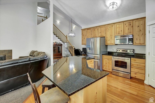10716 N Hayes Cir, Cedar Hills, UT 84062 - kitchen with appliances with stainless steel finishes, a kitchen breakfast bar, light wood-style flooring, dark stone countertops, and open floor plan