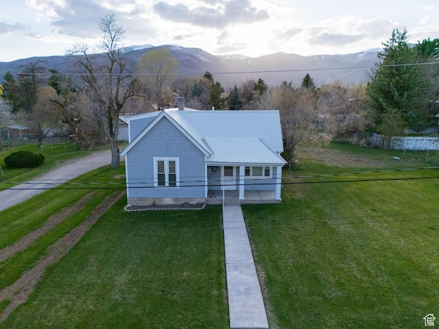view of front of house with a front lawn, a mountain view, fence, and dirt driveway