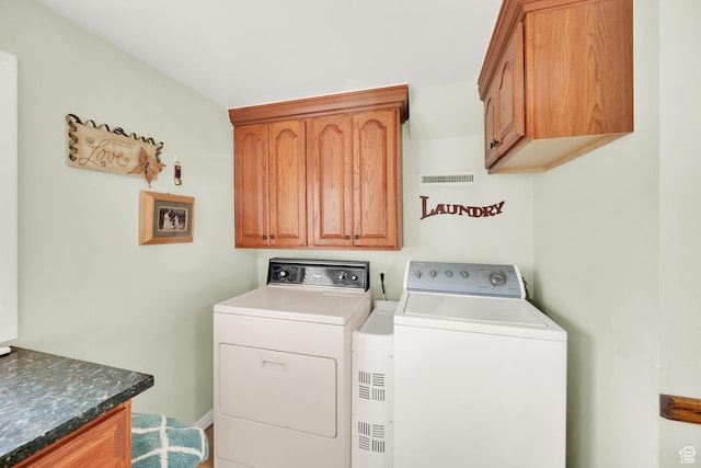 clothes washing area with cabinet space, visible vents, and separate washer and dryer