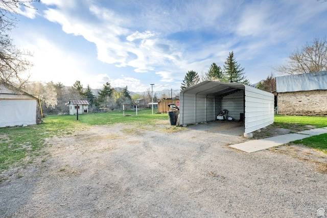 view of parking / parking lot featuring driveway, a shed, and a detached carport