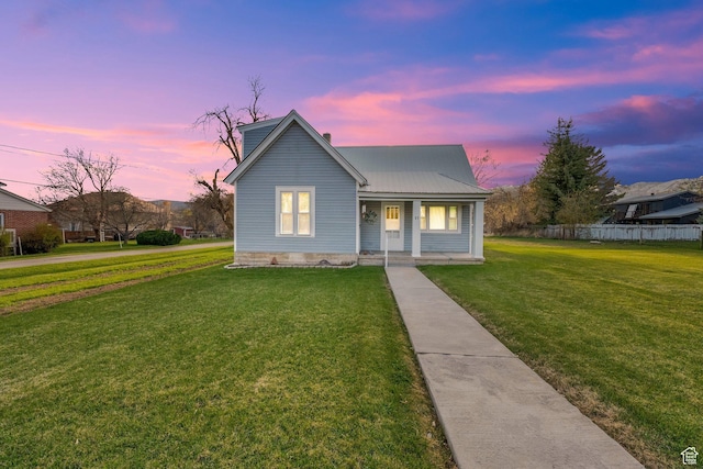 bungalow-style house with fence, a yard, metal roof, and covered porch