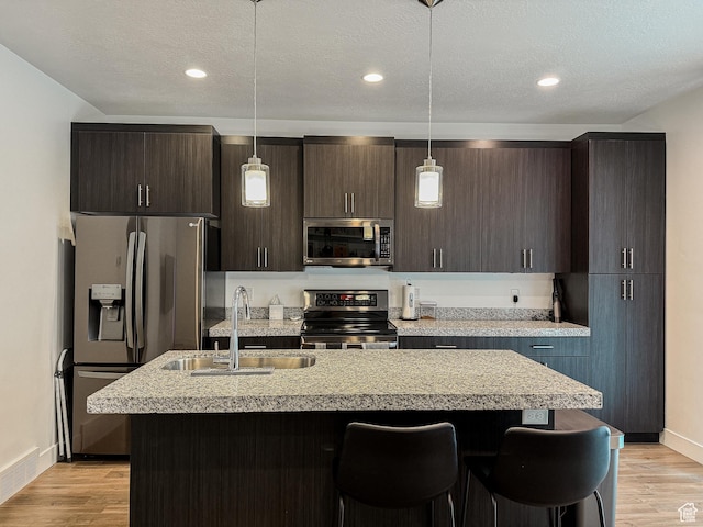 kitchen featuring a sink, a kitchen island with sink, stainless steel appliances, light wood-style flooring, and visible vents