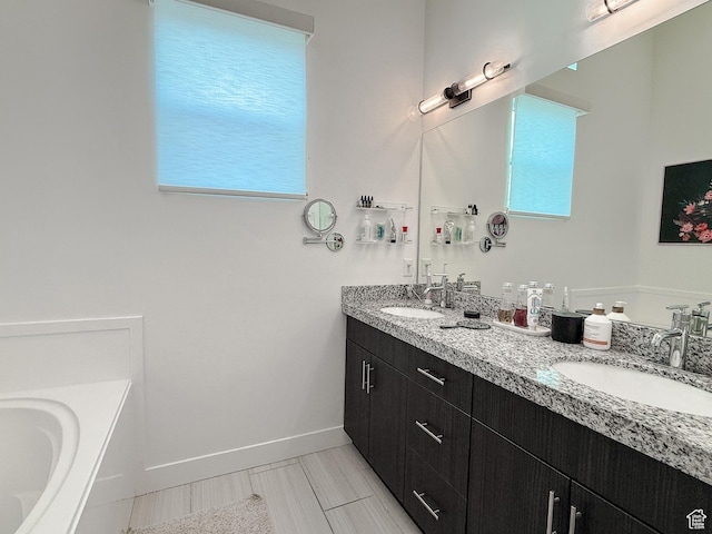 bathroom featuring a healthy amount of sunlight, baseboards, and a sink