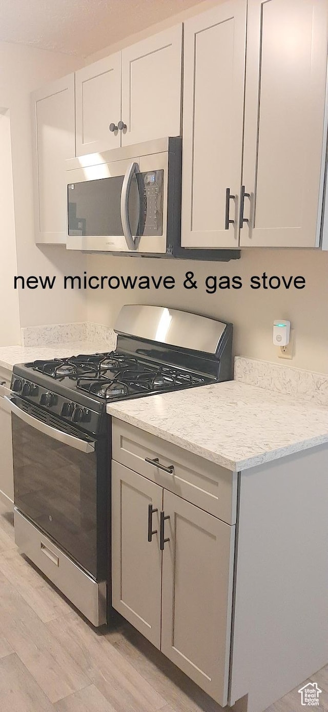 338 E 100 N, Moab, UT 84532 - kitchen with white cabinets, light stone counters, stainless steel microwave, light wood-type flooring, and gas stove