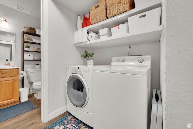 laundry room featuring laundry area, washer and clothes dryer, visible vents, baseboards, and light wood-style flooring