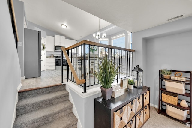 staircase with baseboards, vaulted ceiling, visible vents, and a notable chandelier