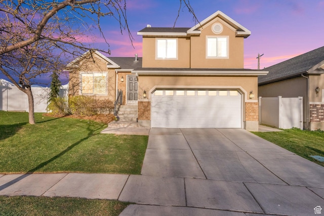 view of front of property featuring a lawn, driveway, an attached garage, fence, and stucco siding