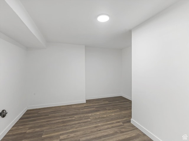 spare room with baseboards and dark wood-style floors