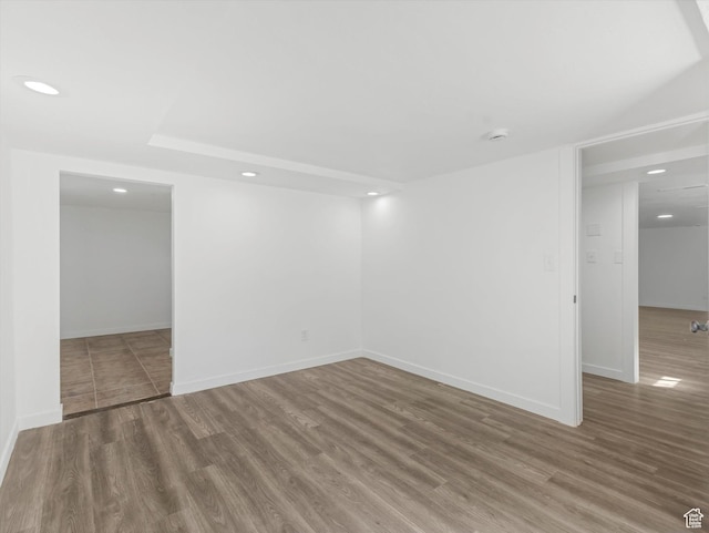 spare room with baseboards, wood finished floors, and recessed lighting