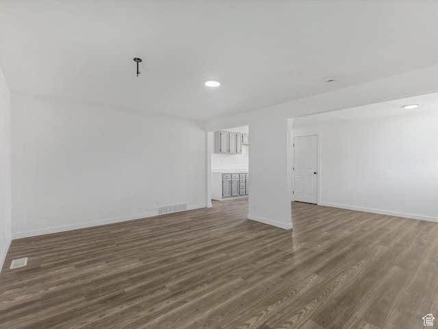 unfurnished living room with visible vents, baseboards, and dark wood-style flooring