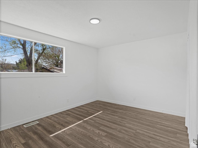 empty room featuring visible vents, baseboards, and wood finished floors