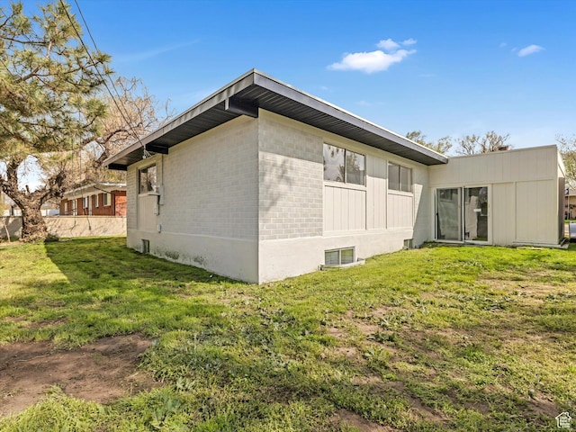 back of house featuring a lawn and brick siding