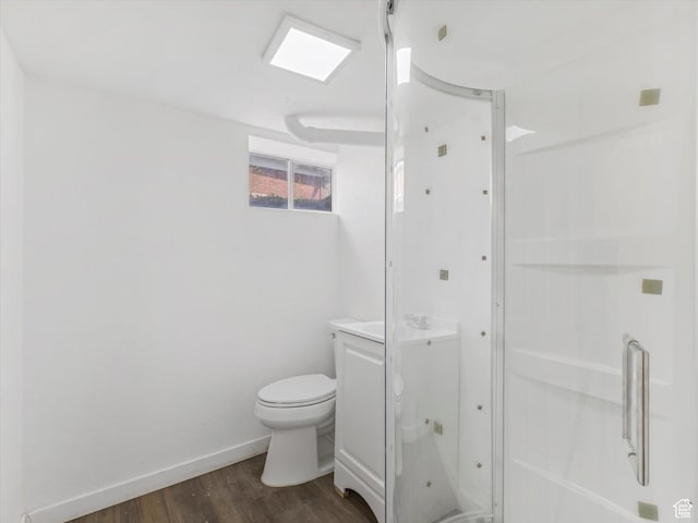 bathroom with toilet, vanity, wood finished floors, and baseboards