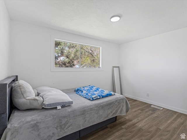 bedroom with baseboards, visible vents, and dark wood finished floors