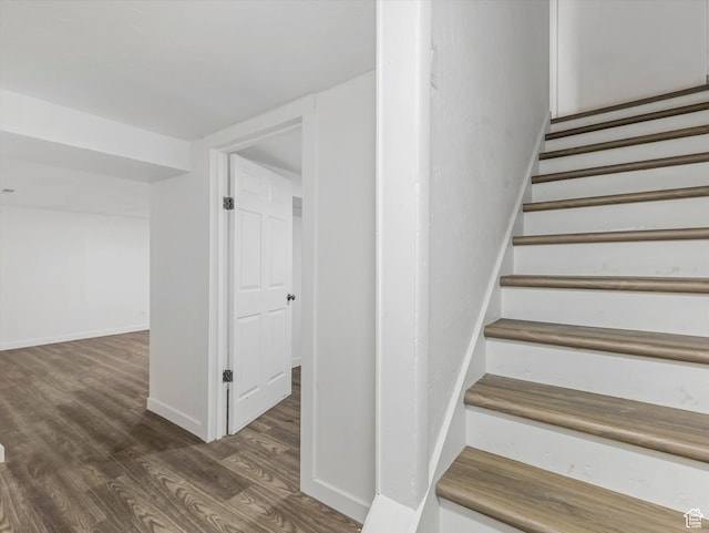 staircase featuring baseboards and wood finished floors