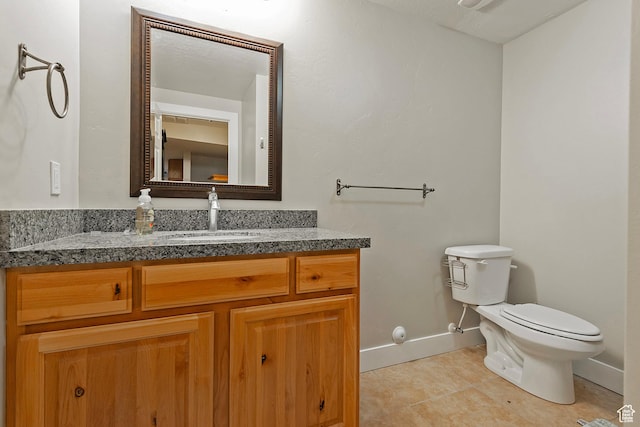bathroom featuring baseboards, vanity, tile patterned flooring, and toilet