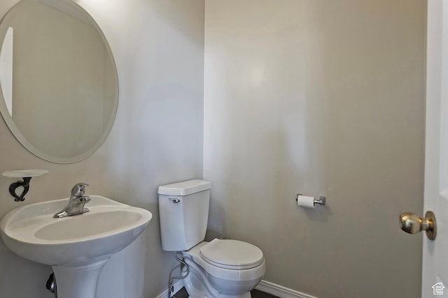 bathroom with baseboards, a sink, and toilet