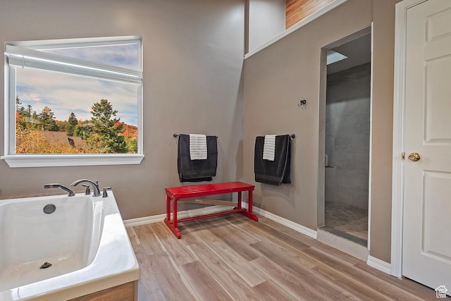 full bath featuring a washtub, baseboards, a tile shower, and wood finished floors