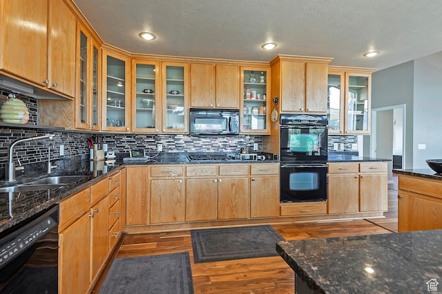 kitchen with a sink, glass insert cabinets, decorative backsplash, dark wood-type flooring, and black appliances