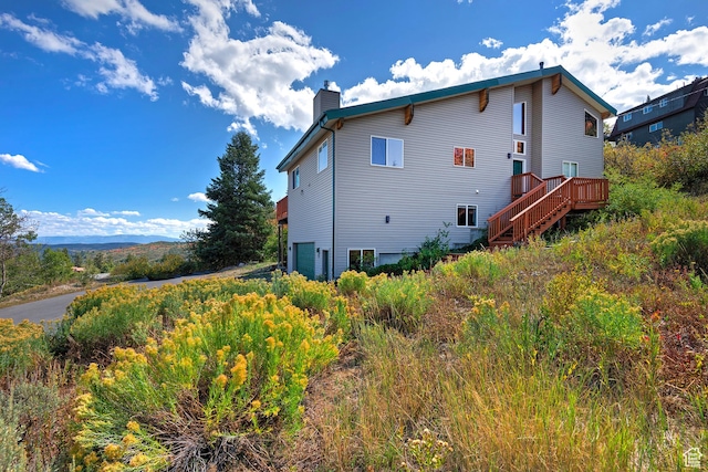 view of home's exterior with stairway, a wooden deck, and a chimney
