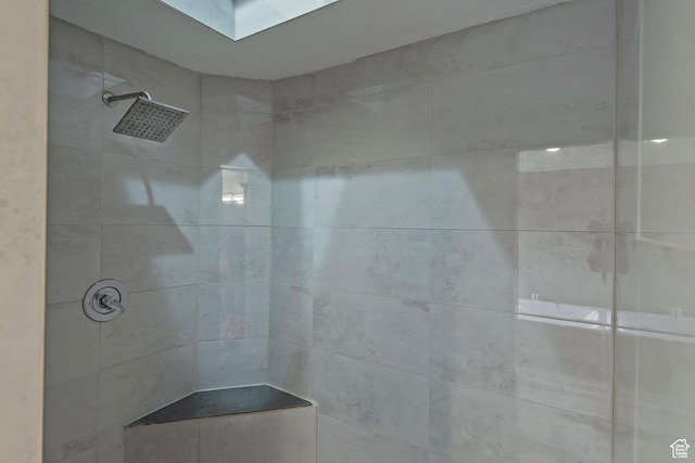 bathroom with a skylight and tiled shower
