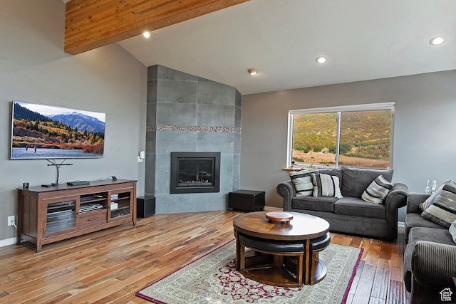 living area with recessed lighting, wood finished floors, baseboards, a fireplace, and high vaulted ceiling