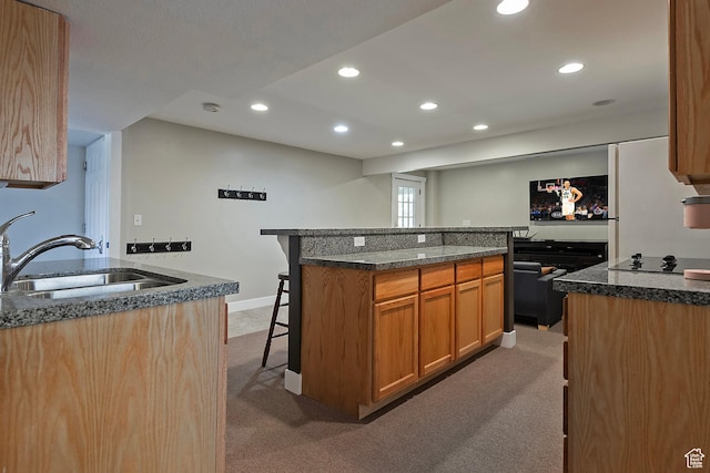 kitchen with recessed lighting, light colored carpet, a breakfast bar area, and a sink