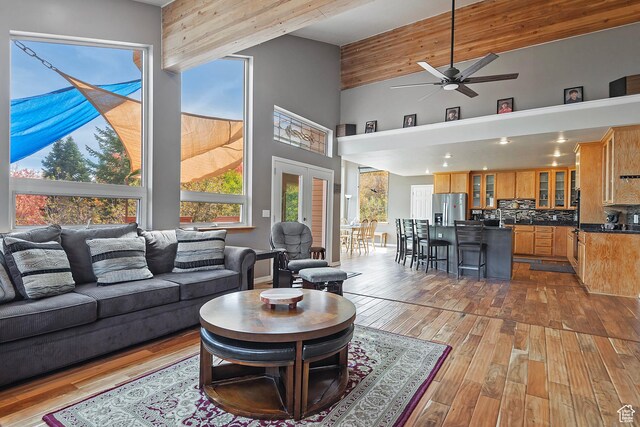 living room with plenty of natural light, wood finished floors, a high ceiling, and ceiling fan
