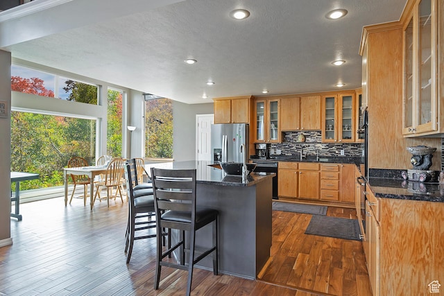 kitchen with a center island, stainless steel fridge, recessed lighting, black dishwasher, and decorative backsplash