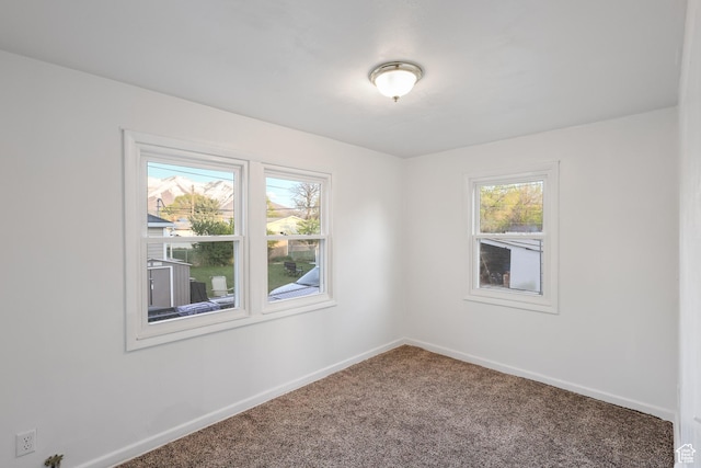 spare room featuring carpet flooring and baseboards