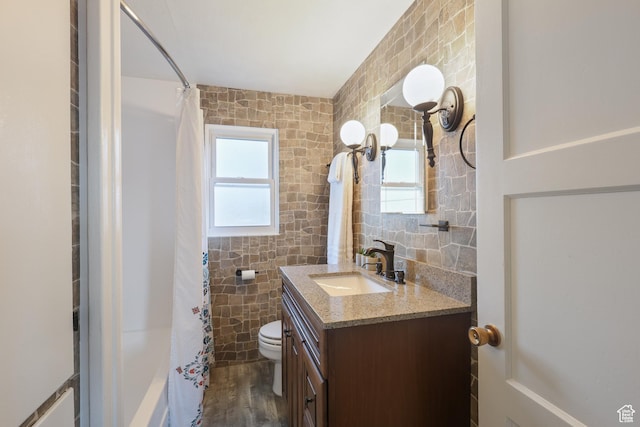 full bath featuring toilet, tile walls, wood finished floors, a shower with shower curtain, and vanity