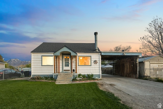 bungalow-style house featuring driveway, a shingled roof, a front yard, and fence