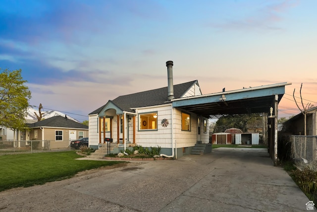 bungalow-style home featuring concrete driveway, an outdoor structure, fence, a yard, and a storage unit