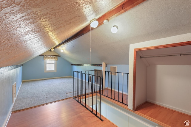 additional living space featuring lofted ceiling, baseboards, wood finished floors, and a textured ceiling