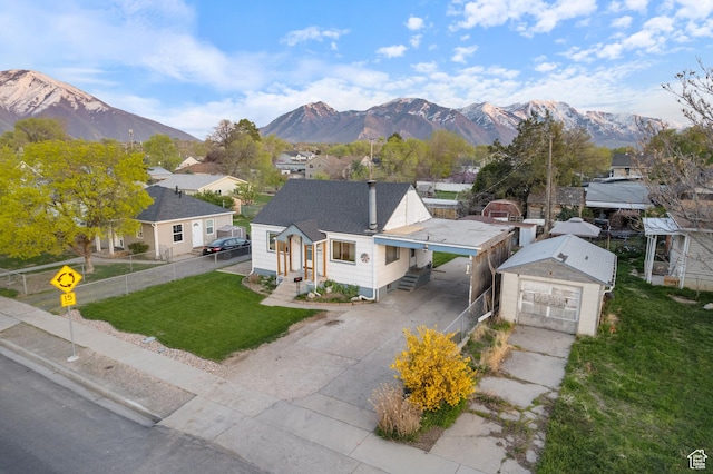 view of front facade with concrete driveway, fence, an attached carport, and a mountain view