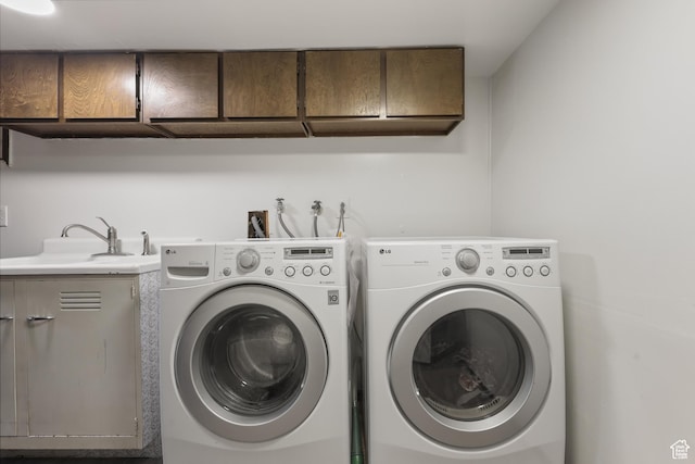 laundry area with washing machine and dryer, cabinet space, and a sink