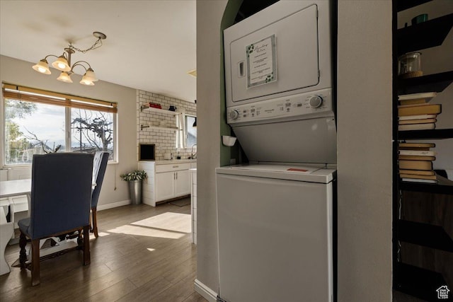 781 N 950 W, Orem, UT 84057 - washroom with stacked washing maching and dryer, an inviting chandelier, dark wood finished floors, baseboards, and laundry area